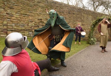 Person in fancy dress as a dragon and another as a knight act out a play