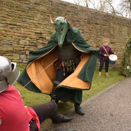 Person in fancy dress as a dragon and another as a knight act out a play