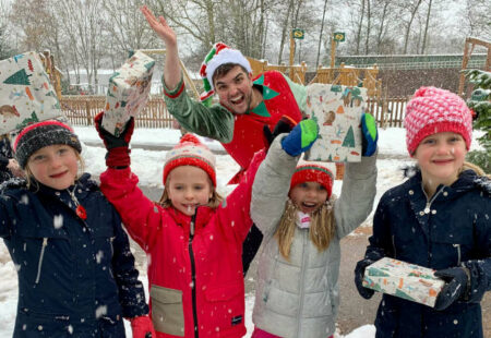 Children holding present with man dressed as an elf at Matlock Farm Park