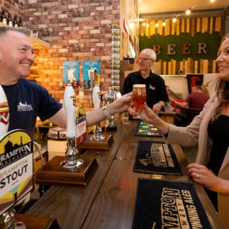 Head brewer serving ale to a female at the brewery bar