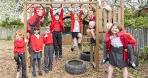 Group of pupils in red Heath Primary uniform playing on wooden monkey bars