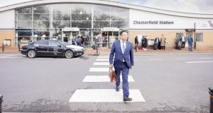 Business man in suit with briefcase crossing at zebra crossing outside Chesterfield Railway Station