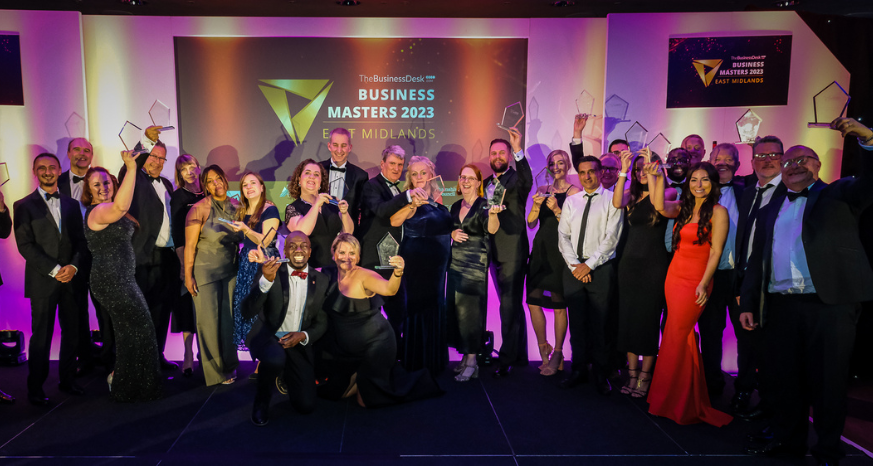 a large group of people holding up awards from the business masters 2023