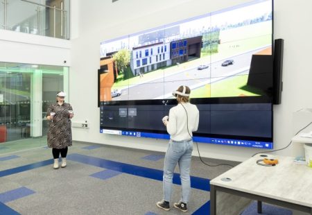 Two women wearing VR headsets and animation on big screen