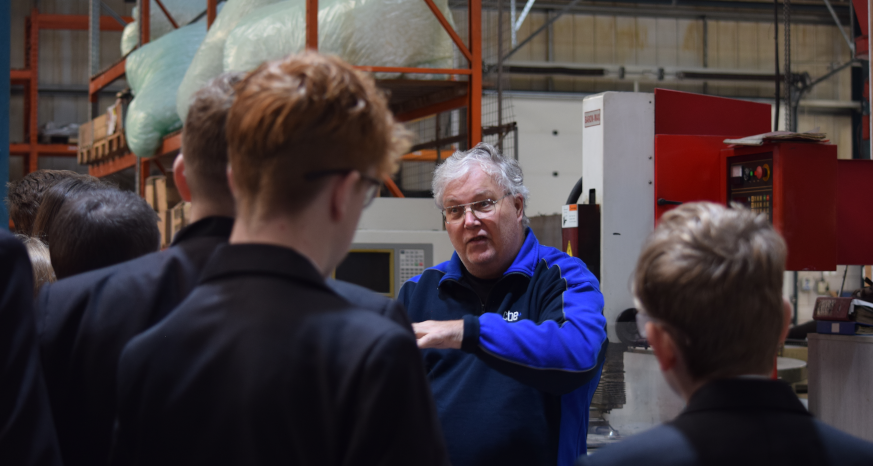 Man talking to a group of students in a warehouse