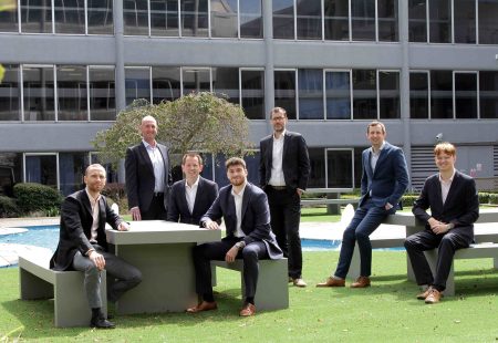 7 males in suits sat around benches in an office garden, representing the team at FHP Property Consultants