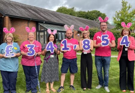 Group of people in pink clothes and bunny ears holding up numbers to signify Ashgate's sparkle walk fundraising total