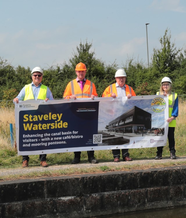 Group of people holding staveley waterside banner wearing hard hats and high viz