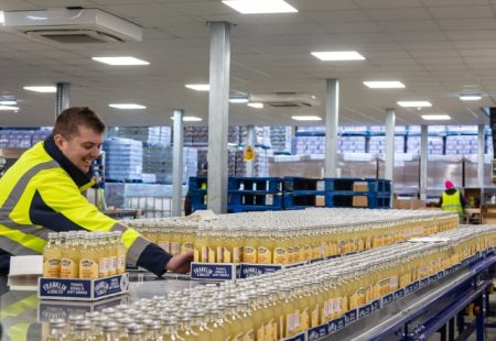 Global Brands drinks factory - bottles on production line being handled by male in high visibility clothing