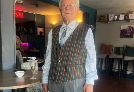 Man with white hair stood in restaurant wearing smart clothing