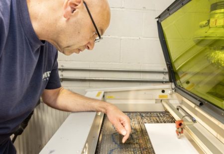 Man stood over machine making a product