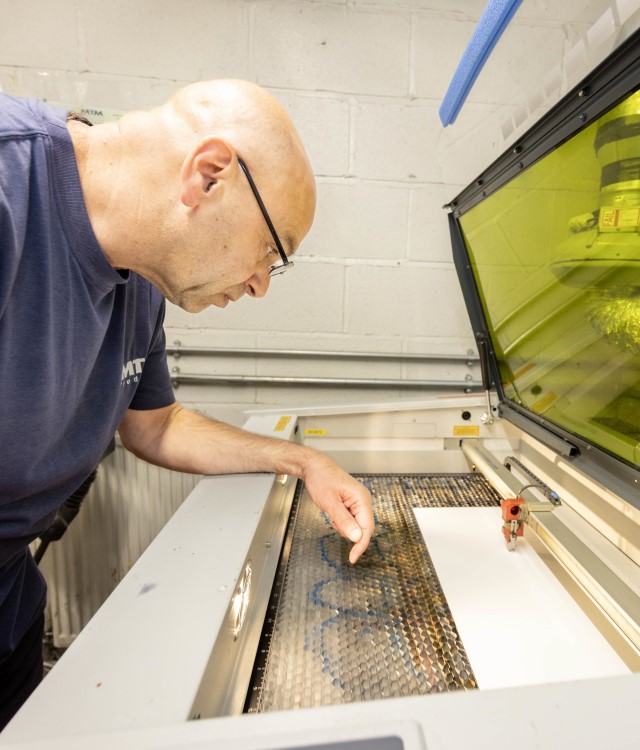 Man stood over machine making a product