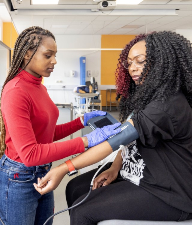 Woman fitting blood pressure machine to another woman's arm