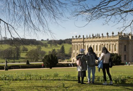 Three children in a field looking at Chatsworth house