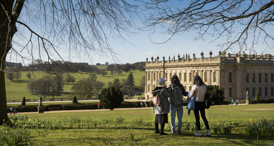 Three children in a field looking at Chatsworth house