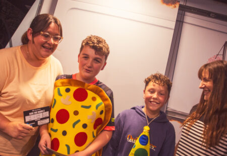 Two women and two boys stood in a line, one boy in a pizza costume