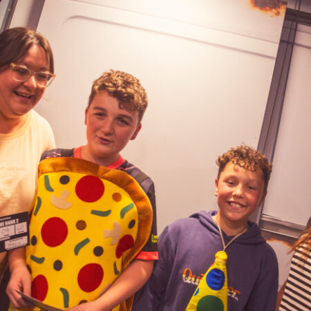 Two women and two boys stood in a line, one boy in a pizza costume