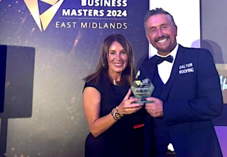 Couple posing with award on stage wearing formal clothing