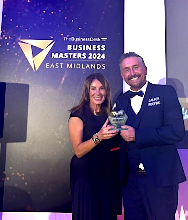 Couple posing with award on stage wearing formal clothing