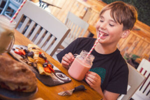 Kid enjoying pancakes and milkshakes at Qoozies