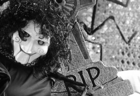 Black and white image of Saw character next to a tombstone saying RIP