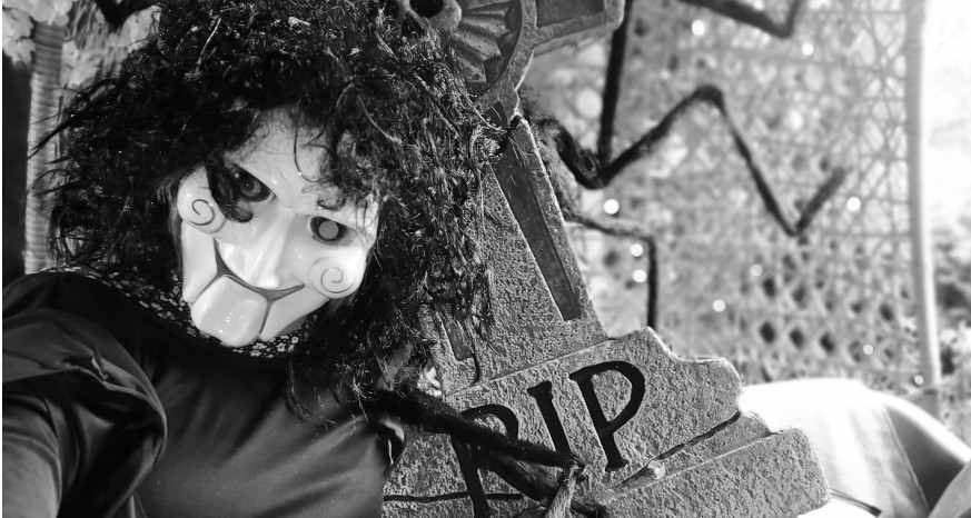 Black and white image of Saw character next to a tombstone saying RIP