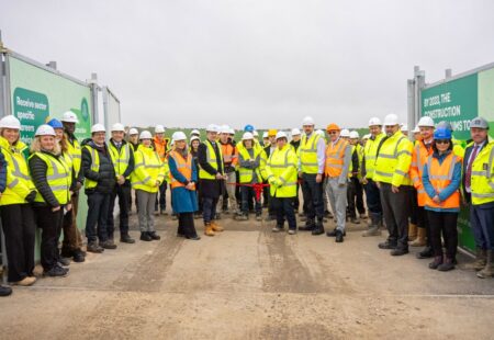 Large group of people wearing high visibiility clothing and hard hats smiling at camera