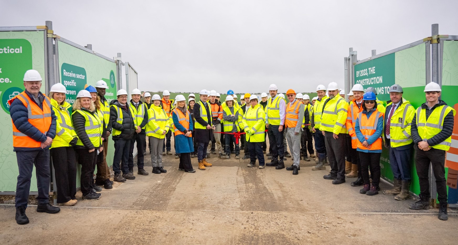 Large group of people wearing high visibiility clothing and hard hats smiling at camera