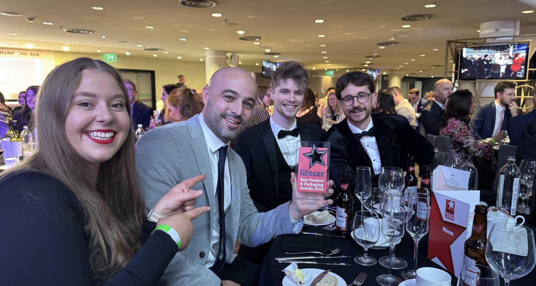 Group of colleagues in formal attire sat at table showcasing award