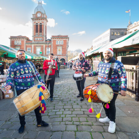 4 men in christmas jumpers with an offer on various instruments