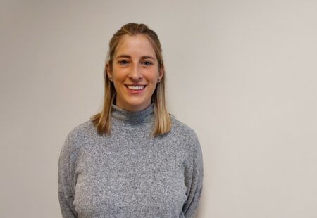 Woman stood in front of light wall smiling