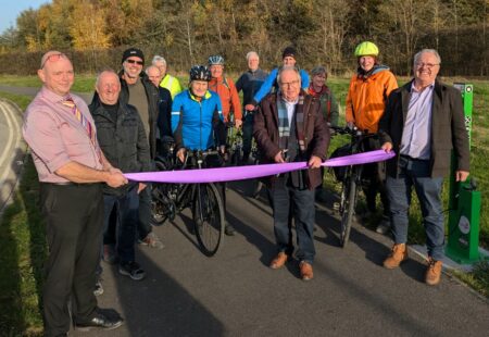 Man cuts ribbon joined by a group of cyclists