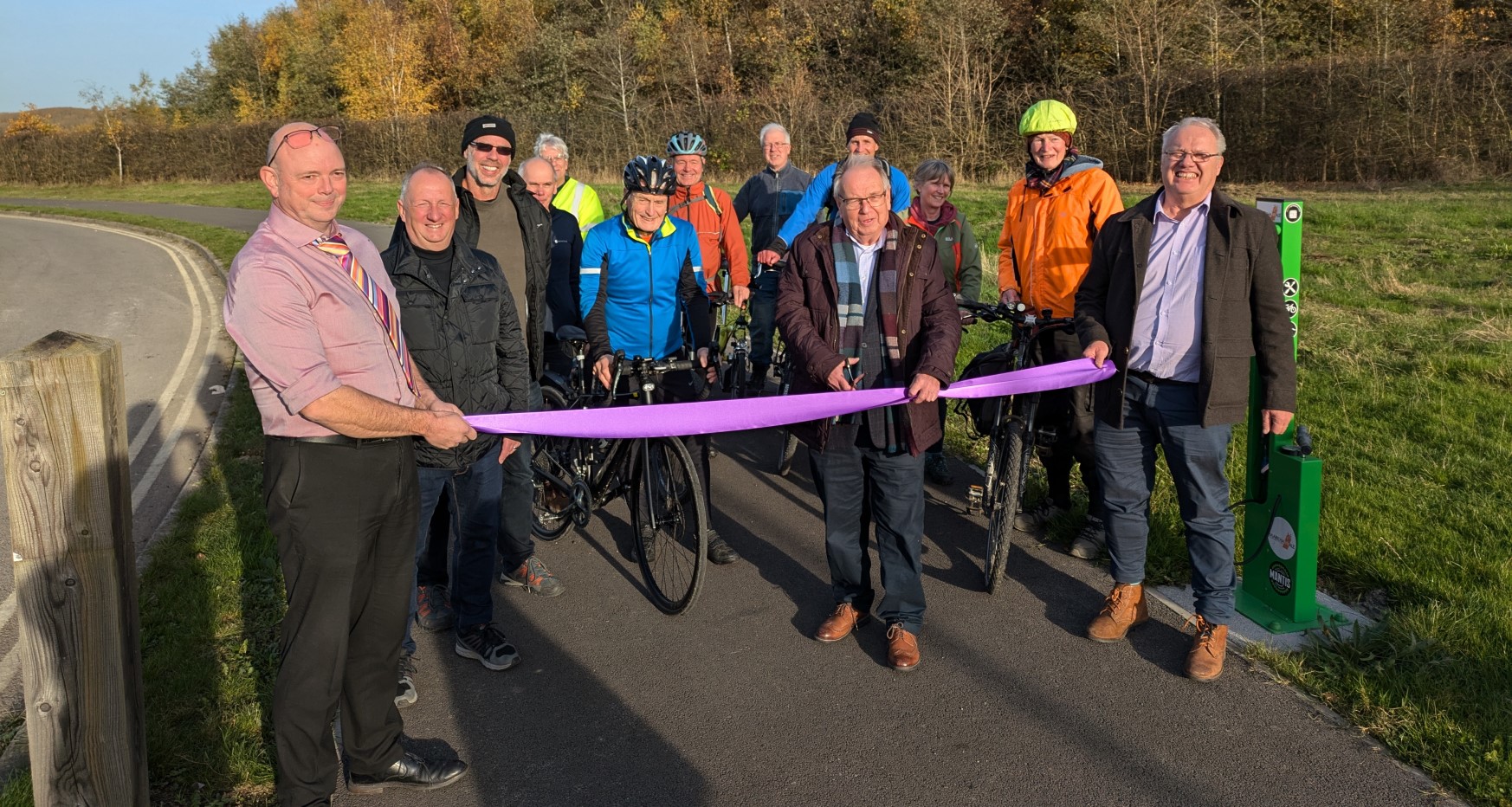 Man cuts ribbon joined by a group of cyclists