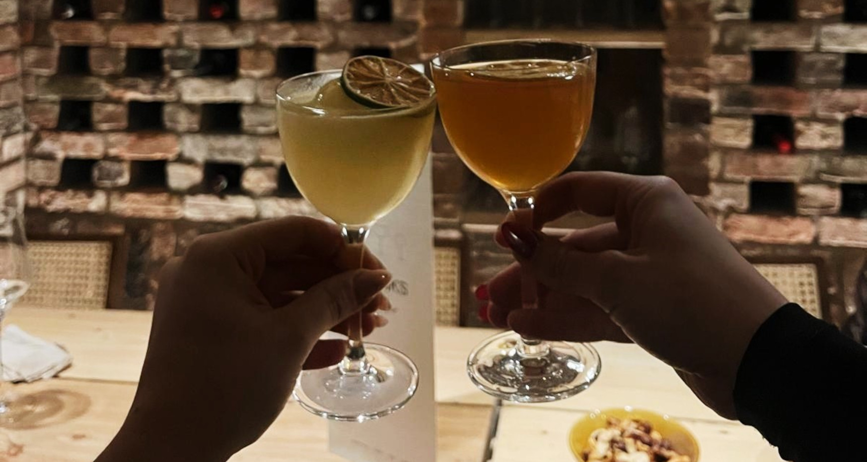 Two cocktail glasses raised as part of a toast