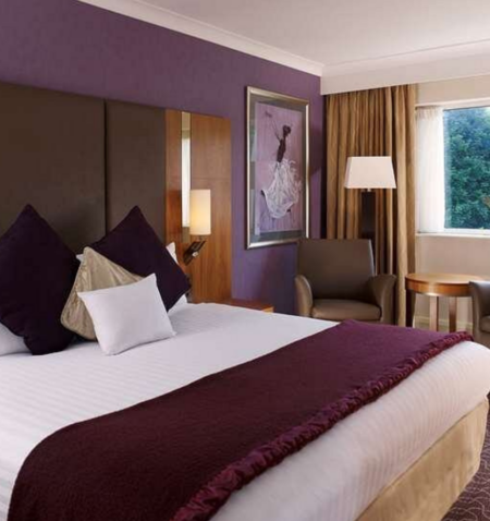 A large hotel bedroom with a neatly-presented king sized bed.