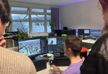 Colleagues collaborate whilst stood near computer